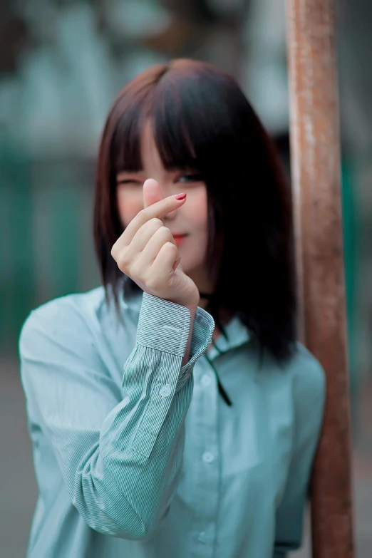 woman in a blue shirt holds her hand to her face