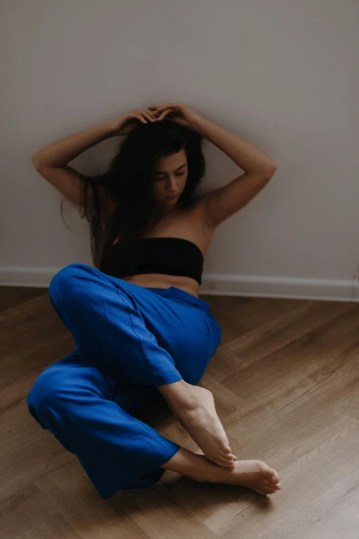 a woman sitting down and wearing blue pants