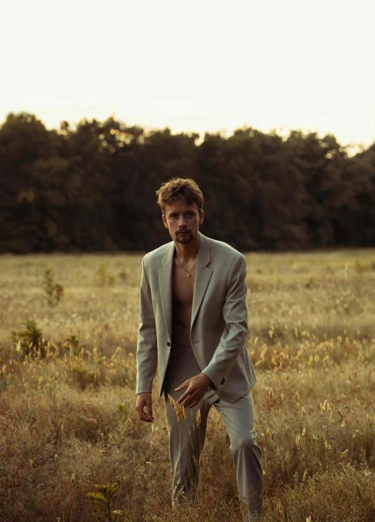 a man standing in a field with his shirt open