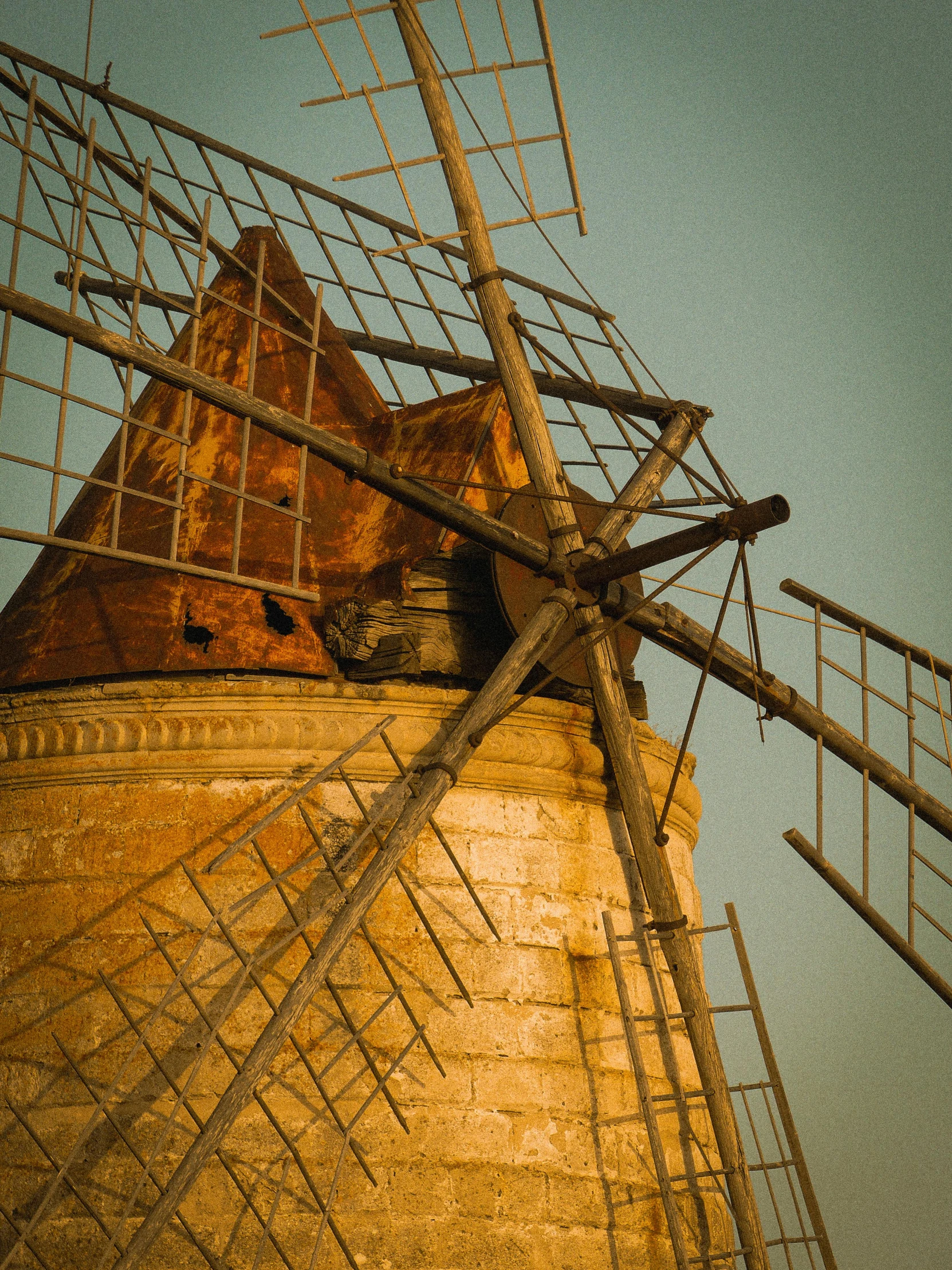 a rusted old windmill with scaffolding and a broken down top