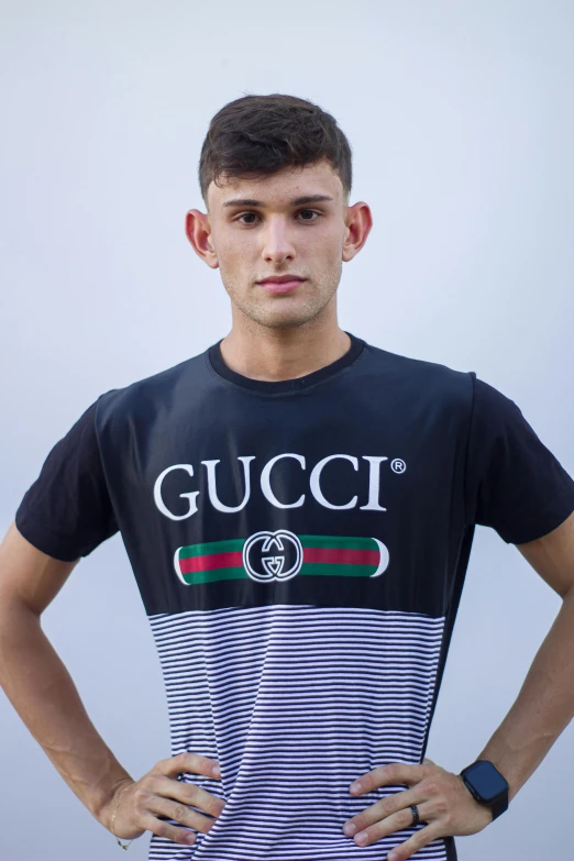 a young man standing with his hands on his hips wearing gucci tee - shirt