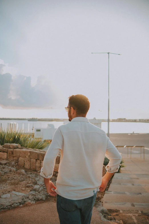 a man wearing a white shirt and jeans walking up a street