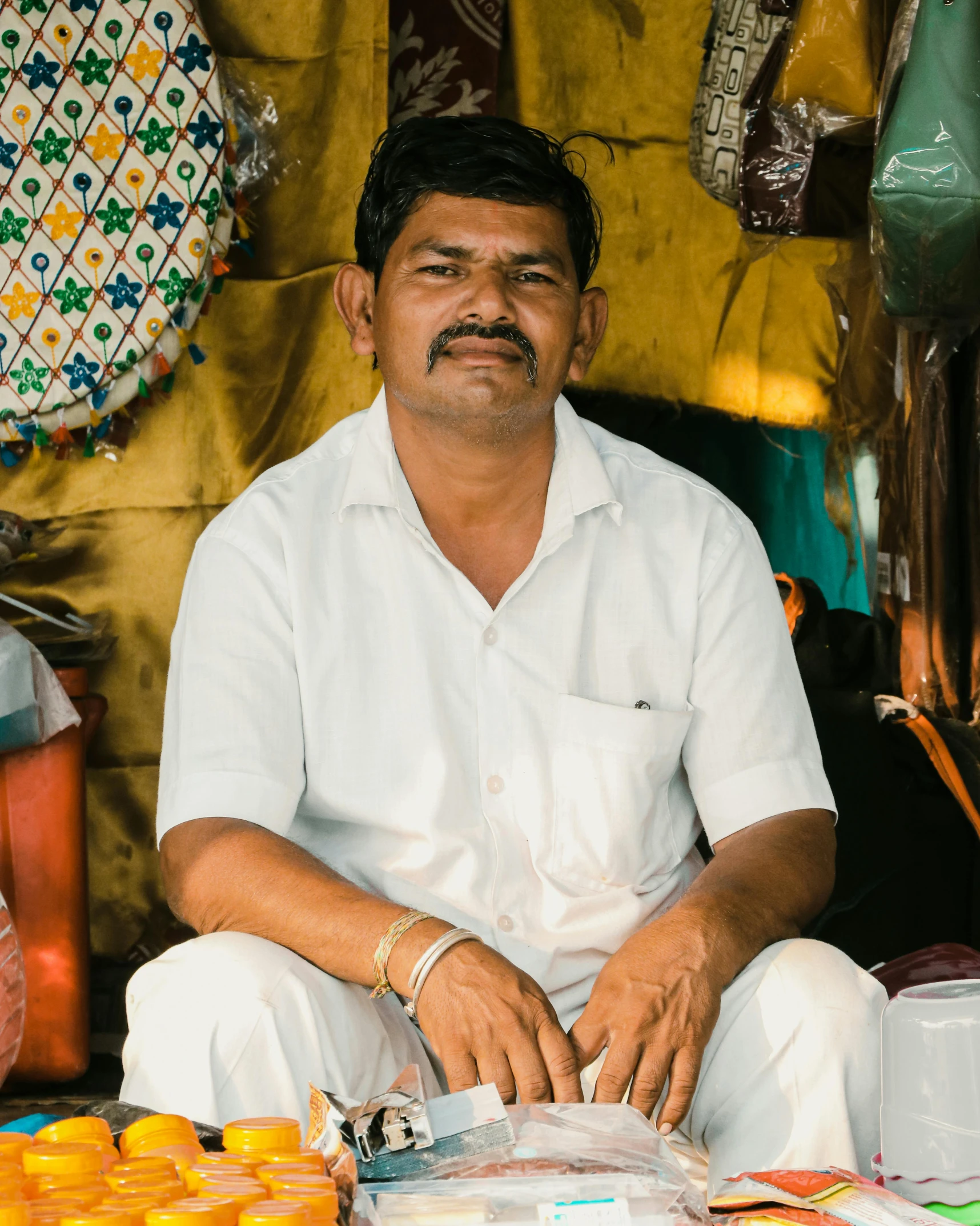 a man sitting on a table outside with some containers and oranges