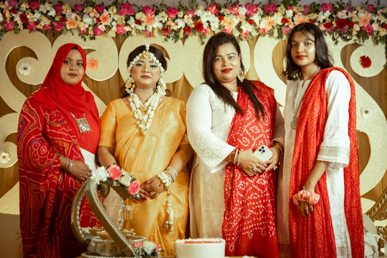 three women in red and white posing next to a cake