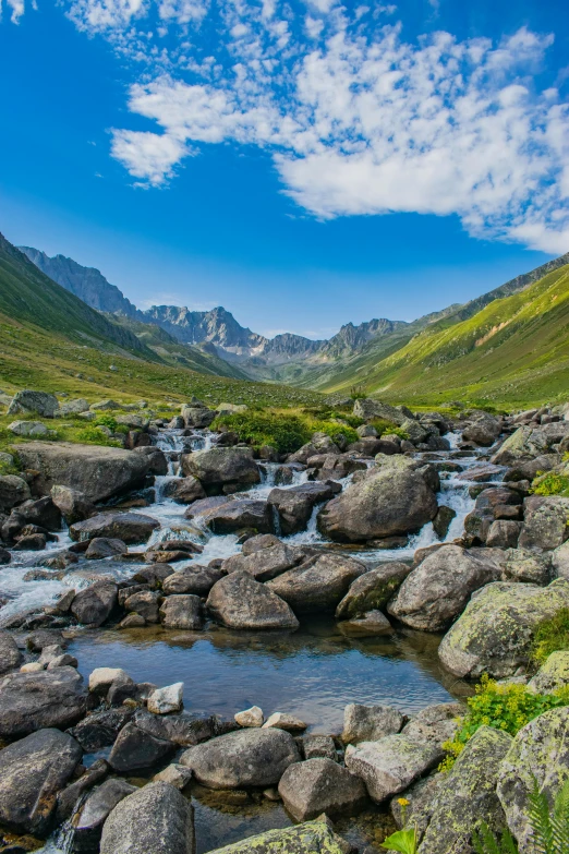 water is flowing over the rocks and grass in the mountains