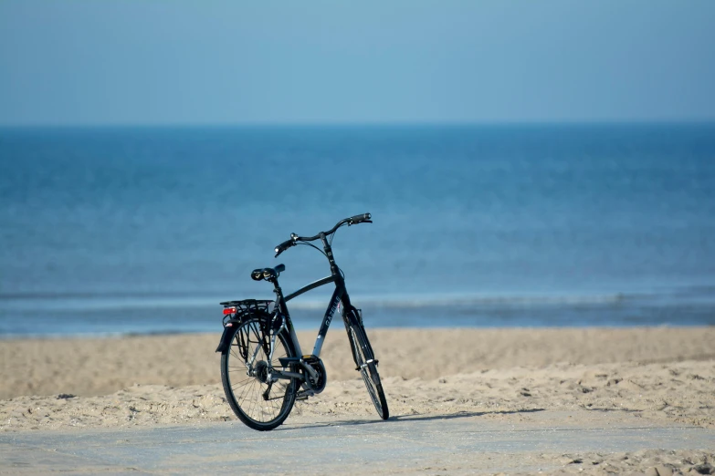 a black bike is leaning up on a beach