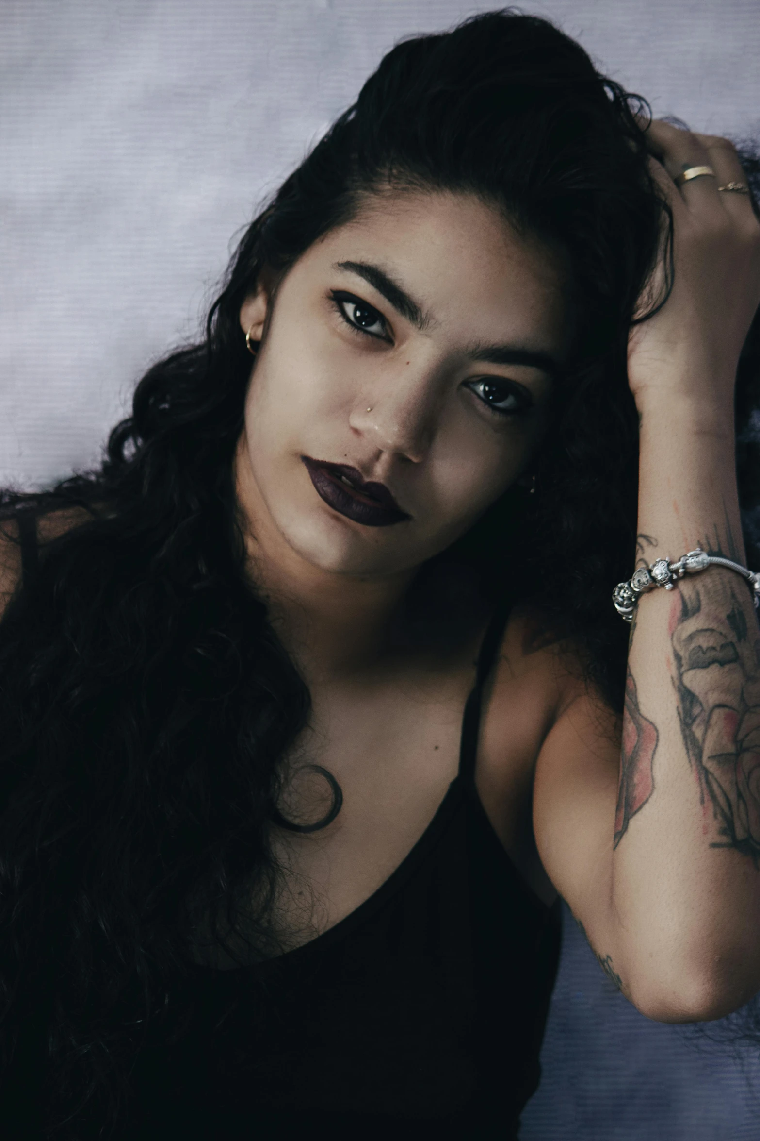 a young woman with tattoos sitting in front of a white backdrop