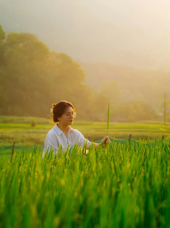 a woman standing in a green field holding up a tall stick