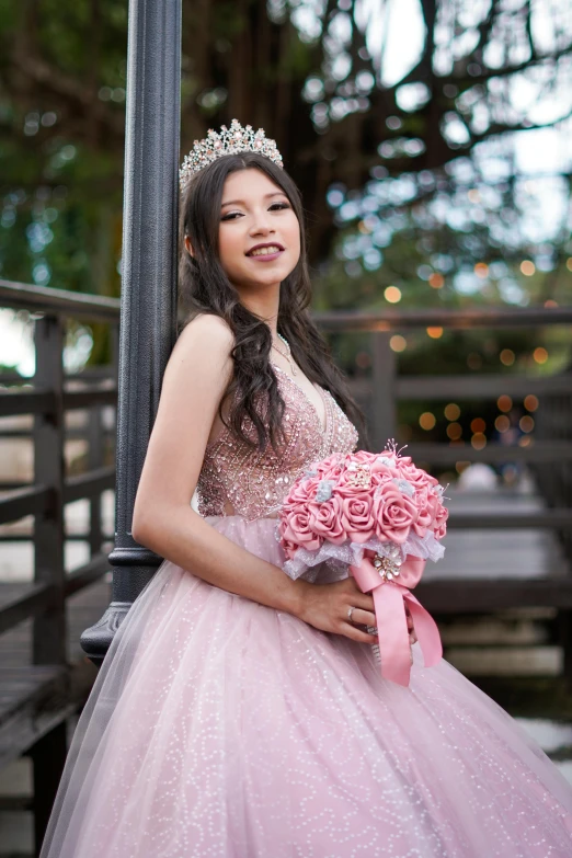 the beautiful young lady in pink gown holds her bouquet