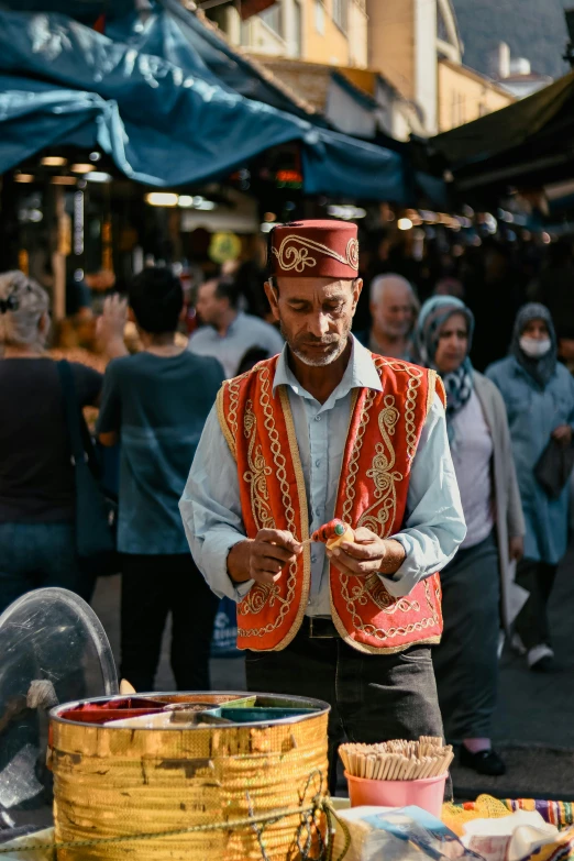 a man in traditional clothing and hat standing near baskets and baskets