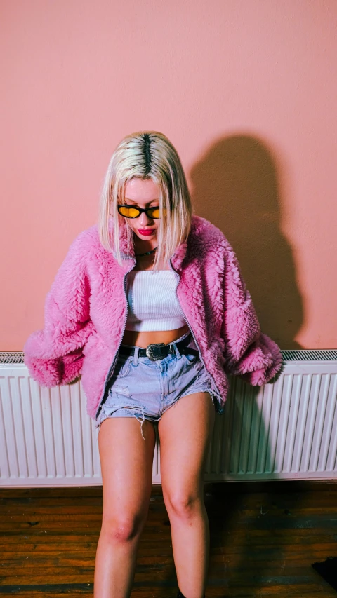 a blonde haired woman with sunglasses, a white tank top, and a pink furry jacket