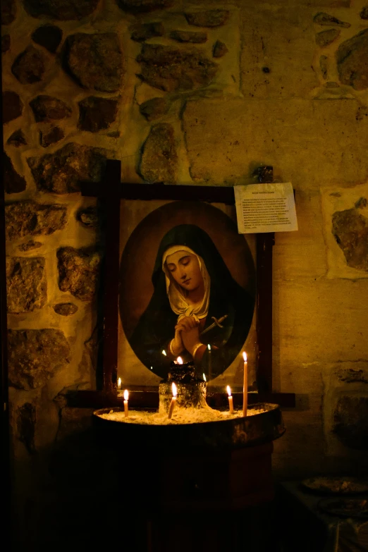 some lit candles around a religious icon of mary