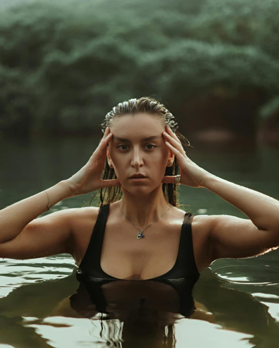 a beautiful woman standing in the water covering her eyes