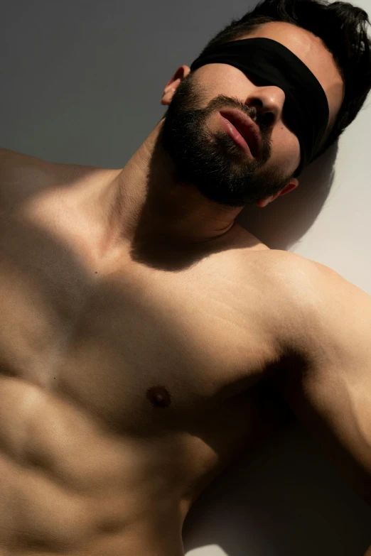 a man with black bandages on his face is posing shirtless