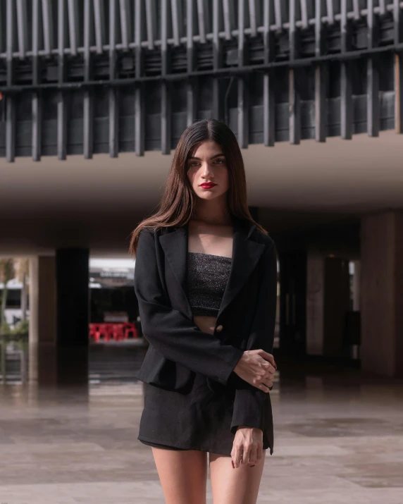 young woman standing alone in a building wearing black shorts and black blazer