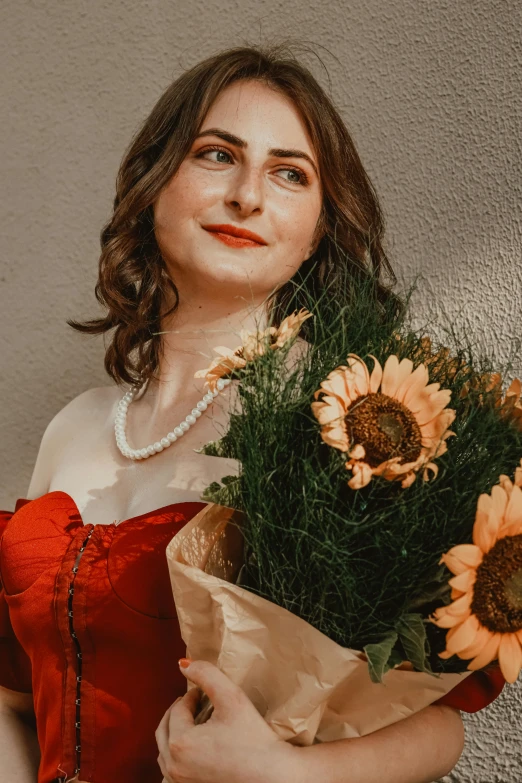 a girl in a red dress is holding some flowers