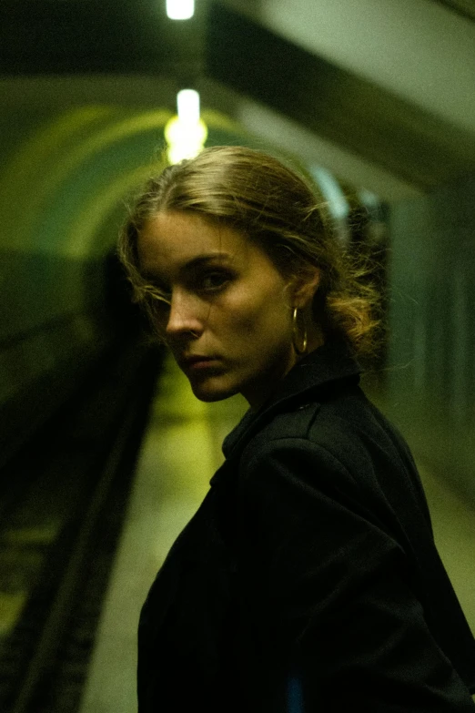 a woman is staring while standing in a subway station