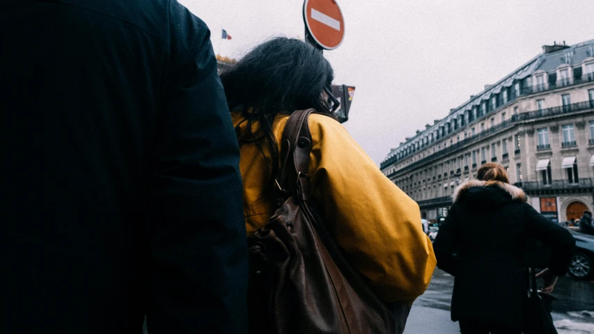 a woman wearing a brown bag walking down a street