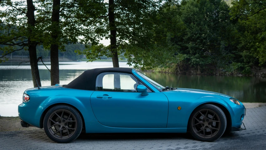 a bright blue sports car parked in front of trees