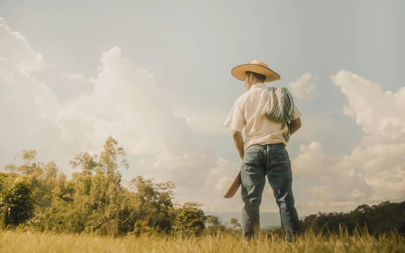 man in cowboy hat standing in a grass field