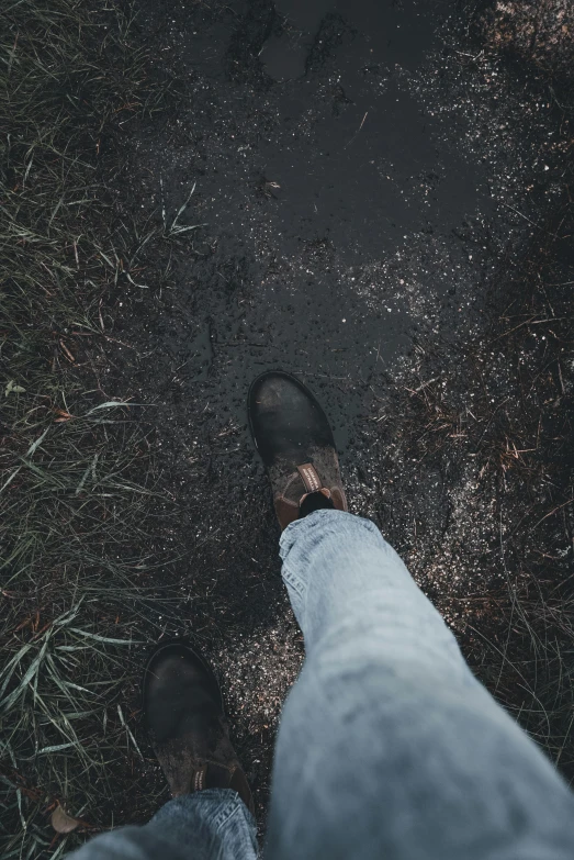 a view from above of a persons feet standing next to grass