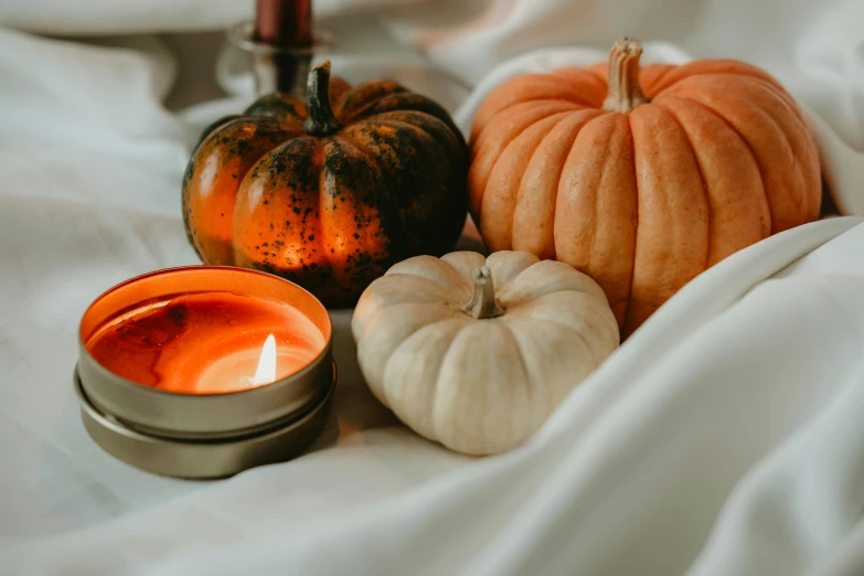 three candles with three pumpkins on the table