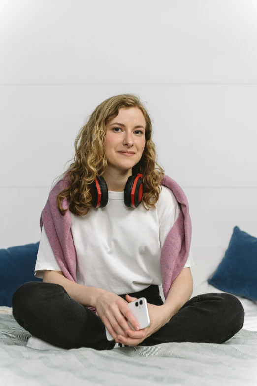 a young woman sitting on the bed holding a video game controller