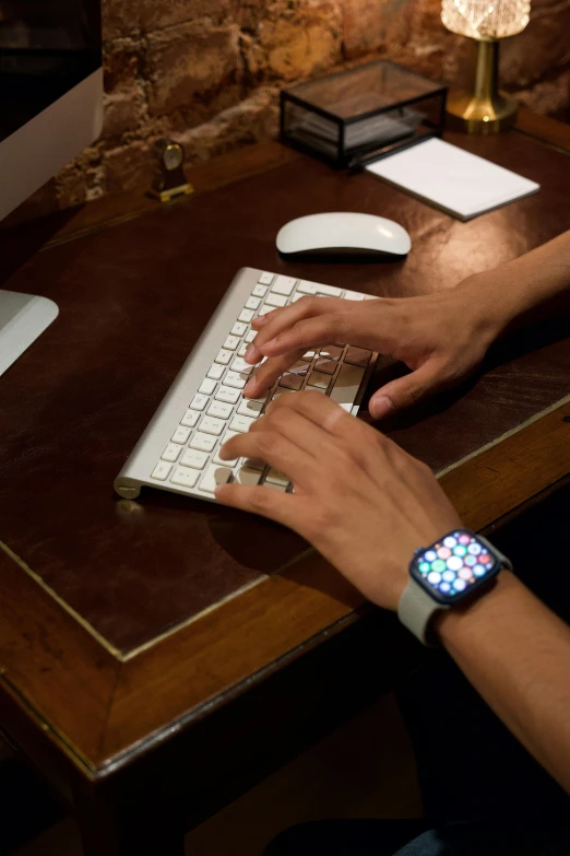 a person typing on a keyboard at a wooden table