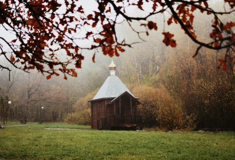 a small wooden structure with a steeple in a field