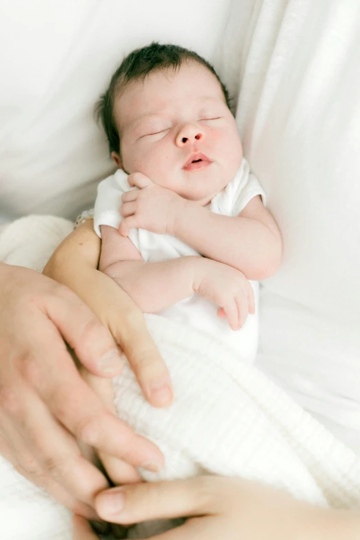 a baby in a person's hand as they sleep