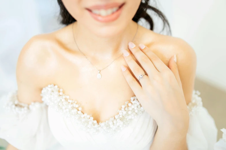 the woman is wearing a necklace with pearls and a diamond on it