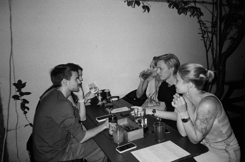 four women sit at a table talking while having drinks