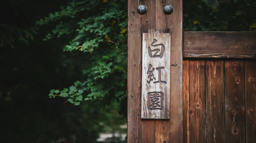 an oriental carved sign hangs on a wooden fence