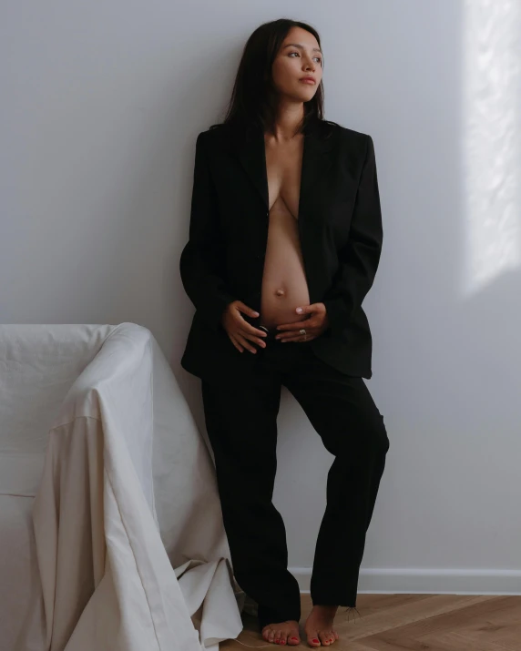 a woman wearing a jacket and pants sitting on top of a white couch