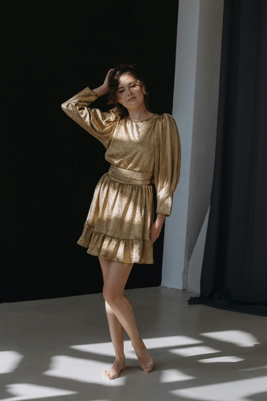 a woman standing wearing a gold dress posing for a picture