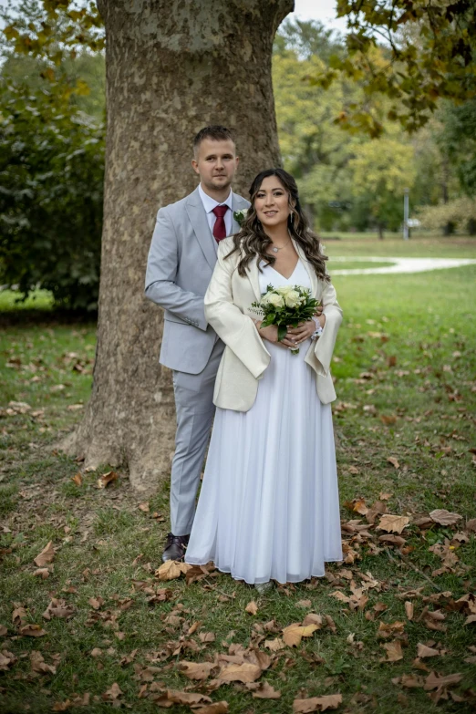 a couple standing in front of a tree dressed in all white