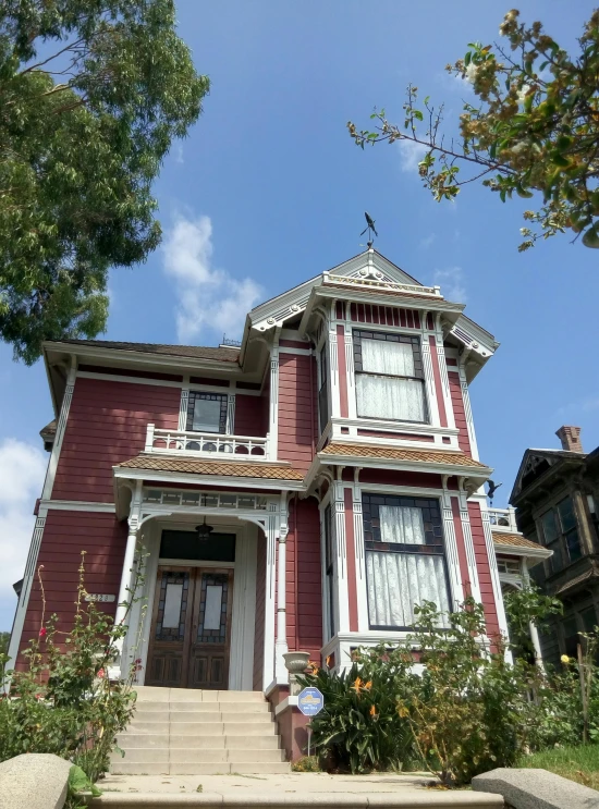 a small red house with a porch and stairs to the second floor