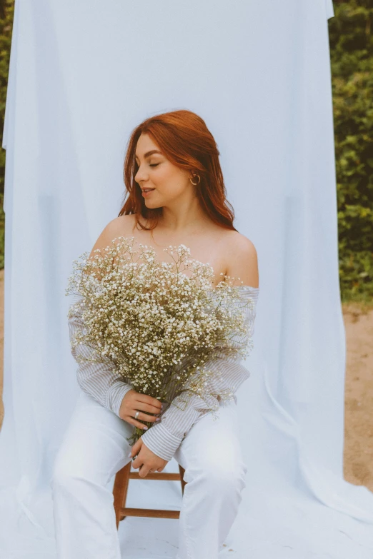 a woman holding flowers sitting on top of a chair