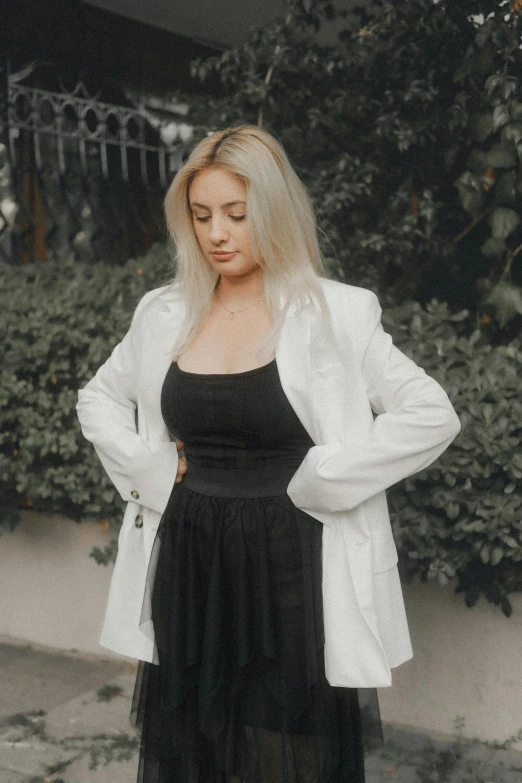 a woman wearing black is standing in front of a bush