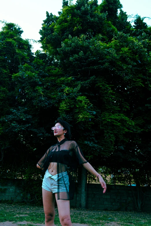 a women in short shorts standing next to a tree