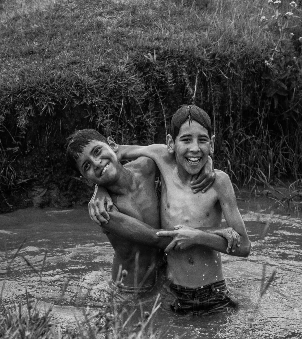 two young men carrying each other in water