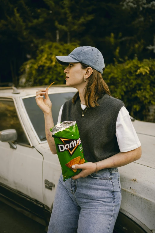 a woman standing next to a car and holding a donut bag