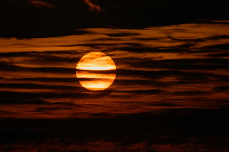 a full moon rising over clouds and the horizon