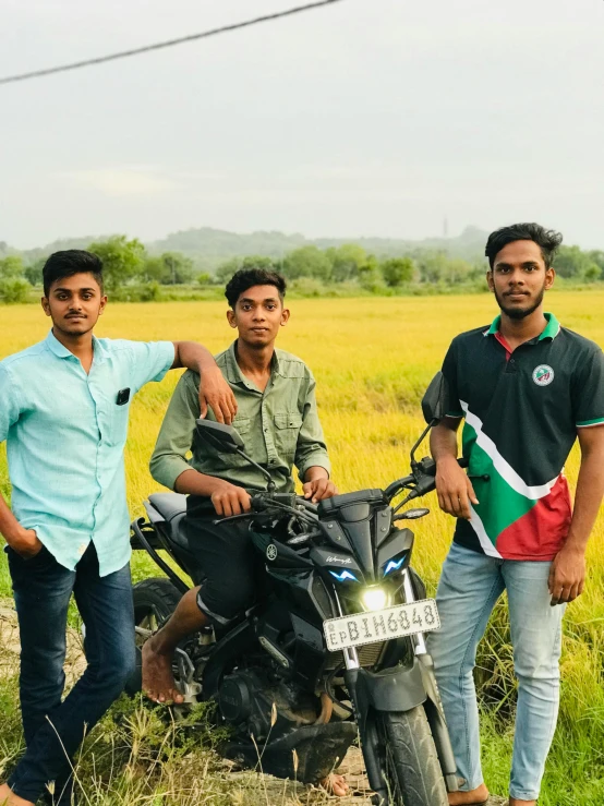 two men and one woman are on their motorcycle in the field