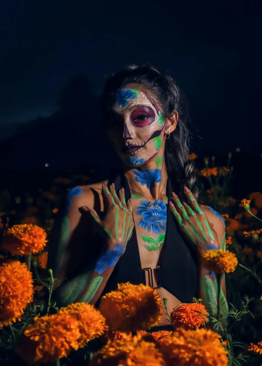 a woman with body paint on her hands is standing in orange flowers