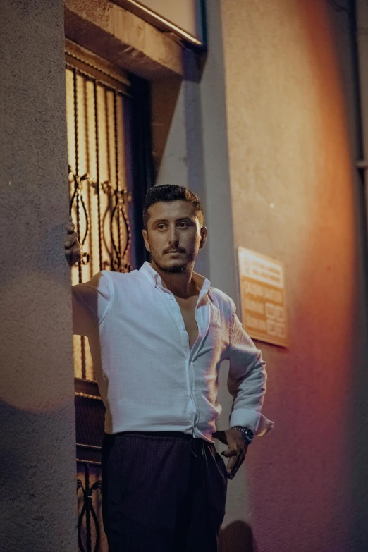 a man with a white shirt standing in front of an iron gate