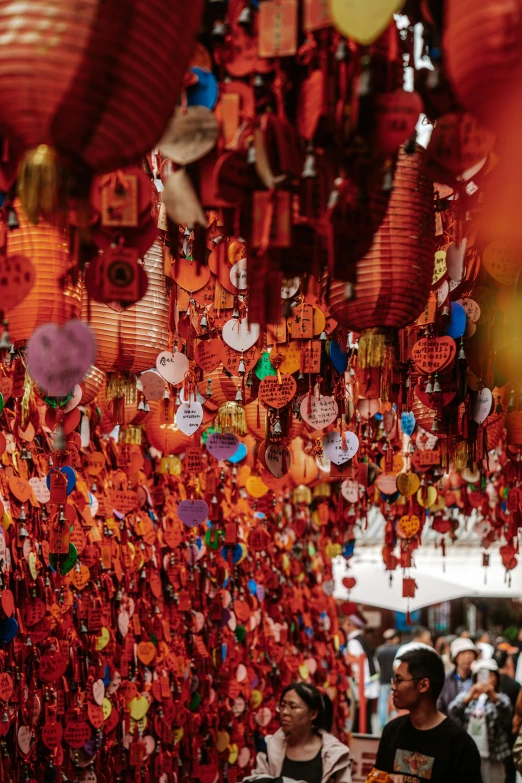 people standing under some red lanterns hanging from the ceiling