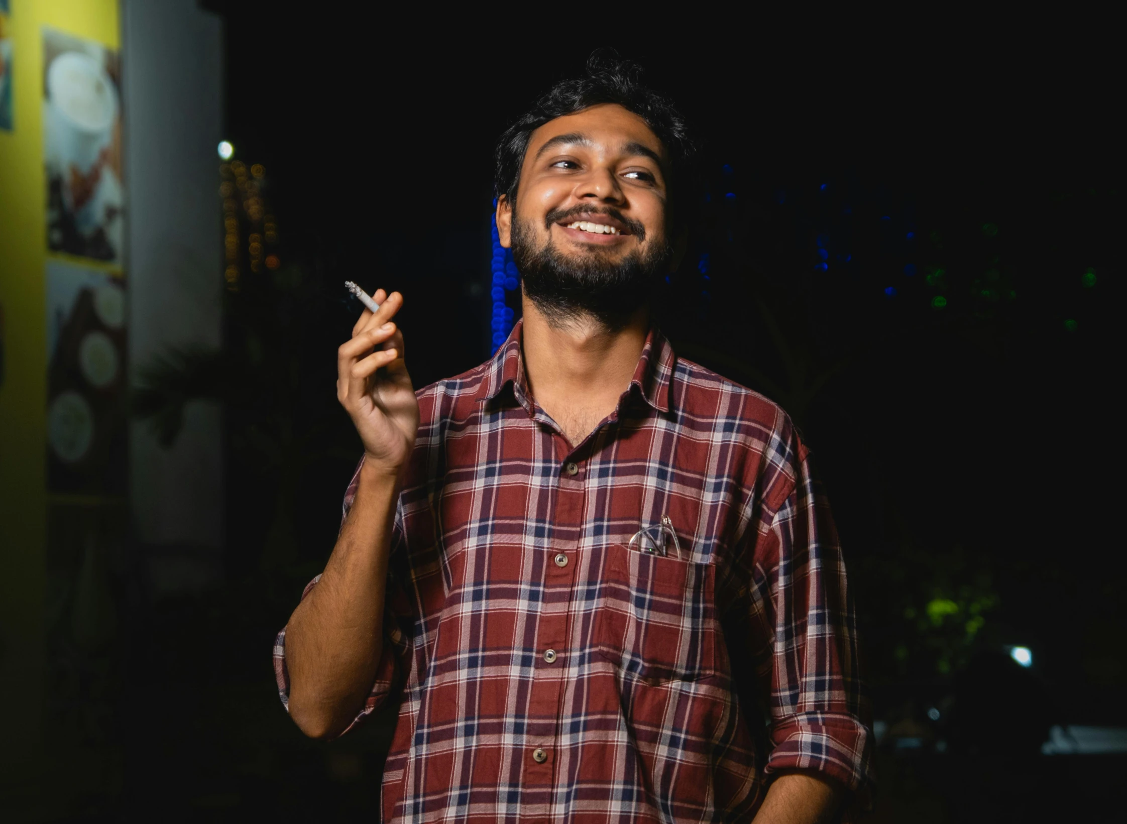 a bearded man is smoking a cigarette outside