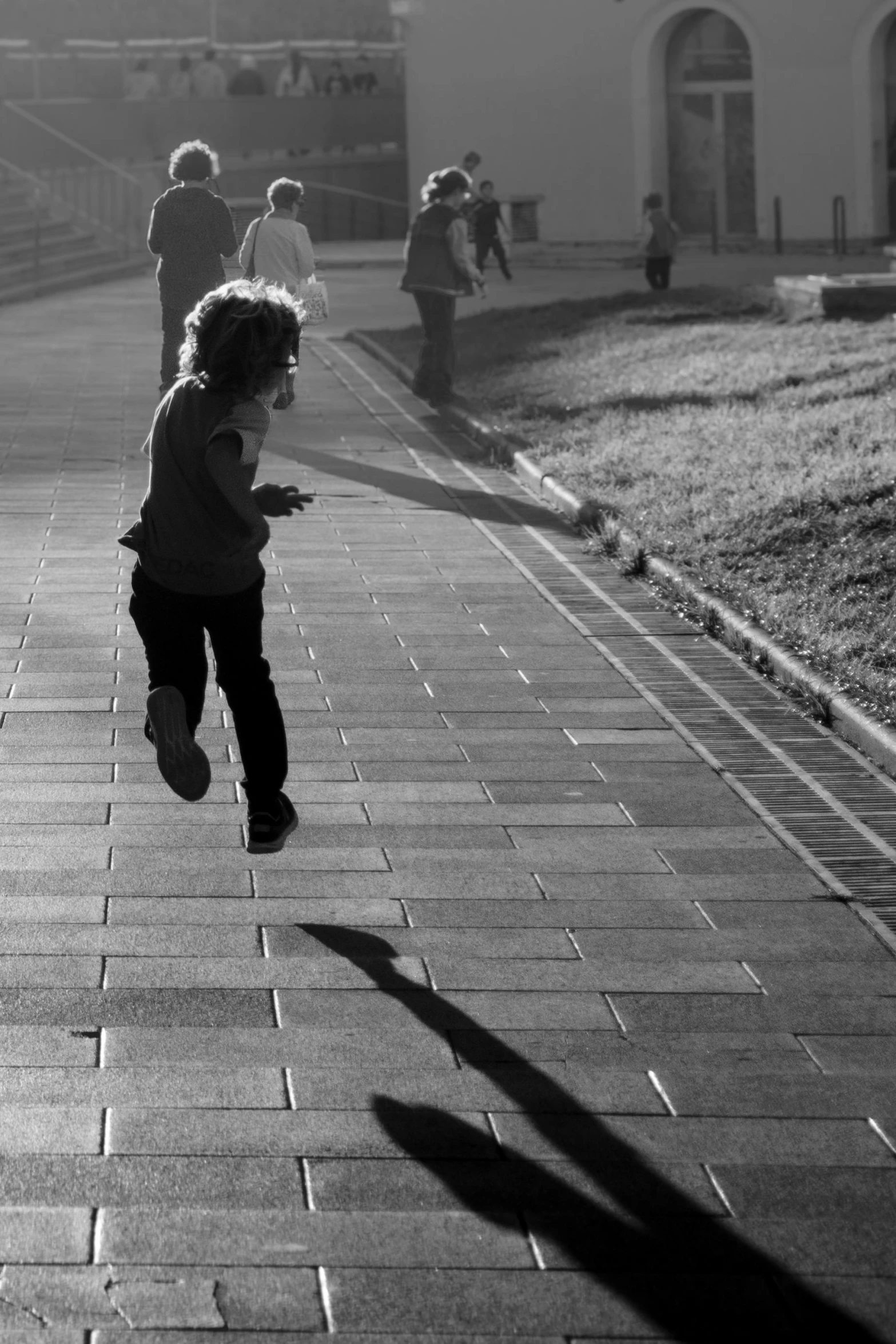 the child runs across the sidewalk as people watch