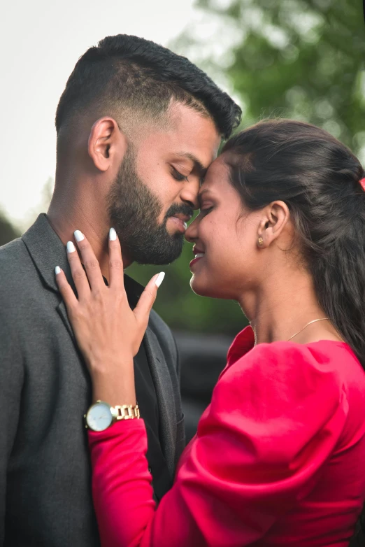 couple kissing while standing together near trees